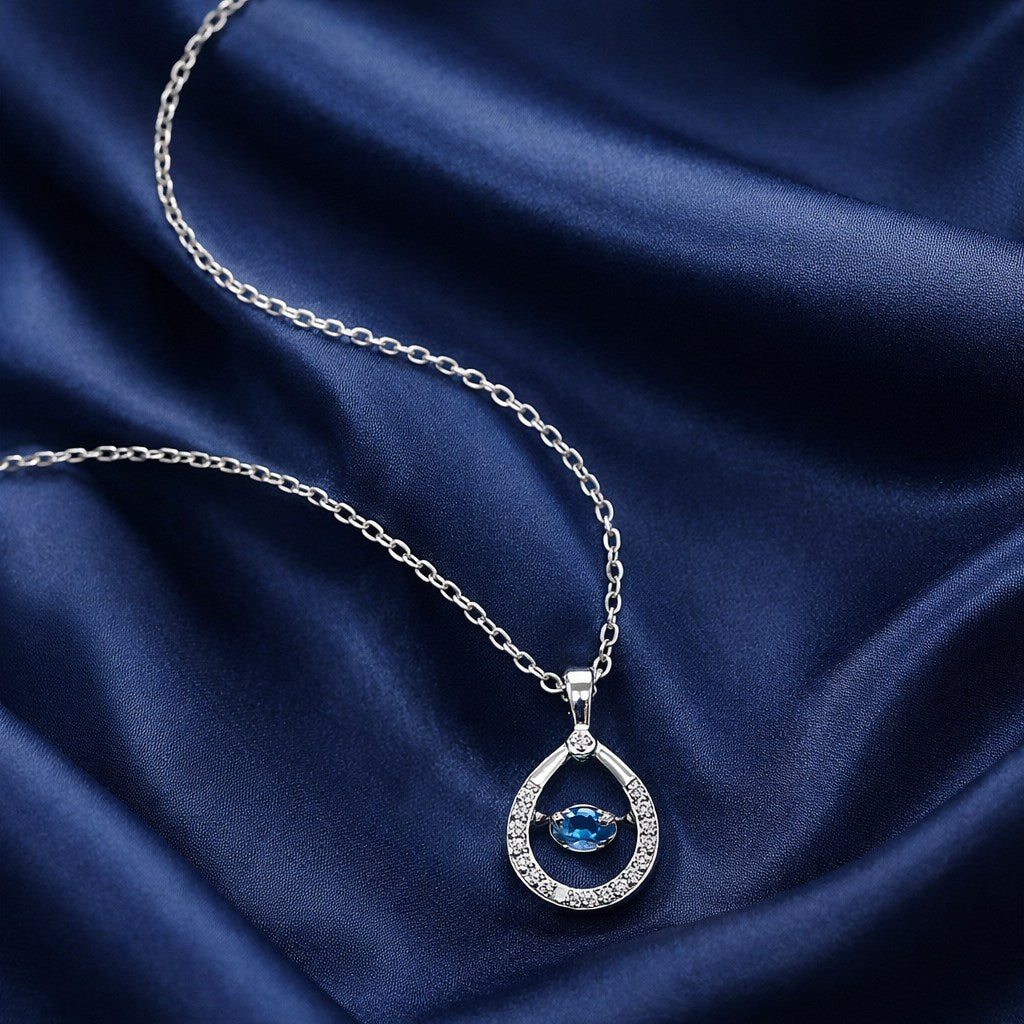 925 sterling silver teardrop pendant necklace with blue dancing stone on fabric background”