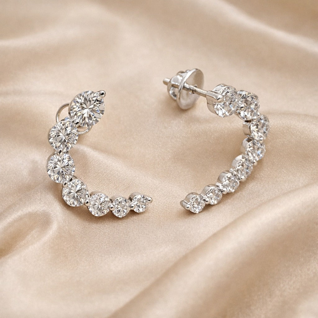 Silver drop earrings with cz stones on a beige satin background