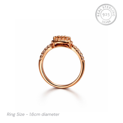 Rose gold ring with gemstones on a white background, featuring 'Real Sterling 925' stamp.