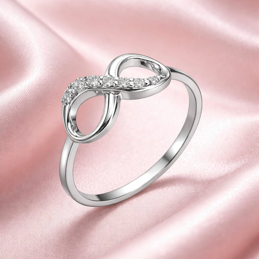 Silver infinity ring with cz stones on a pink satin background