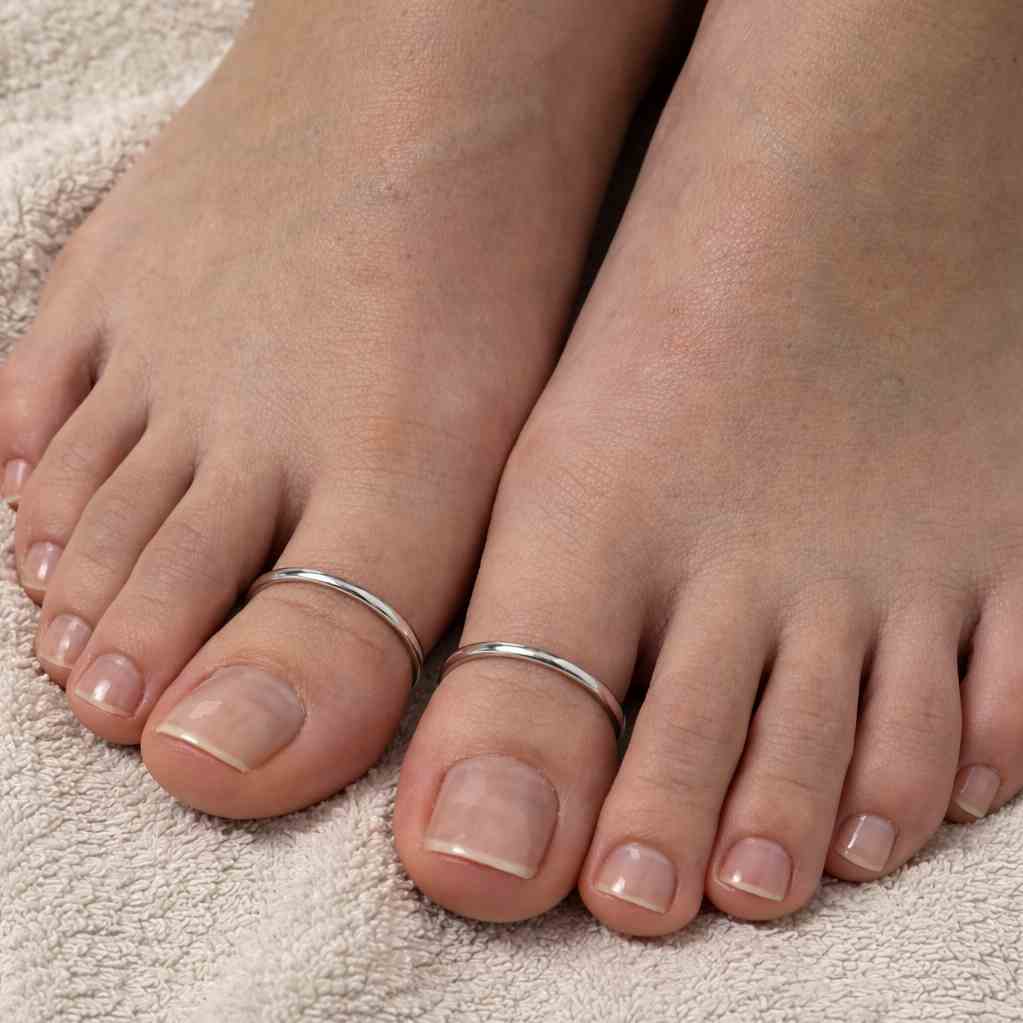 Close-up of feet with silver thumb plain toe rings on a textured surface