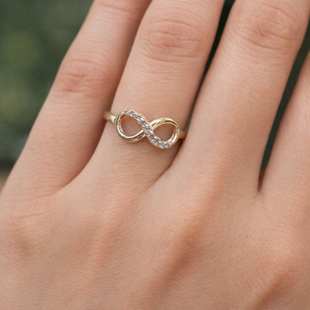 Silver infinity ring on a person's finger with a blurred background